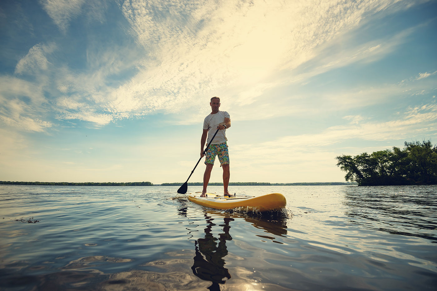 man using a stand up paddle board at a nature mental health retreat
